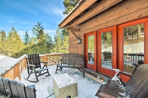 Eine Holzhütte mit roter Tür und einer überdachten Veranda mit Schaukelstühlen und einer Bank.