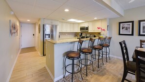 Une cuisine moderne dotée d’un îlot central, de tabourets de bar et d’un coin repas avec une table et des chaises.