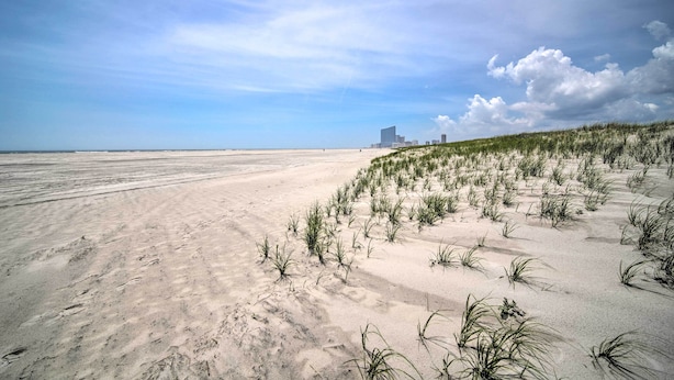 Une plage avec des dunes de sable et une végétation clairsemée.