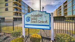 Une enseigne indiquant l’entrée du complexe hôtelier Brigantine Island Beach Resort, offrant une vue dégagée sur les bâtiments du complexe et sur une zone délimitée par une clôture.