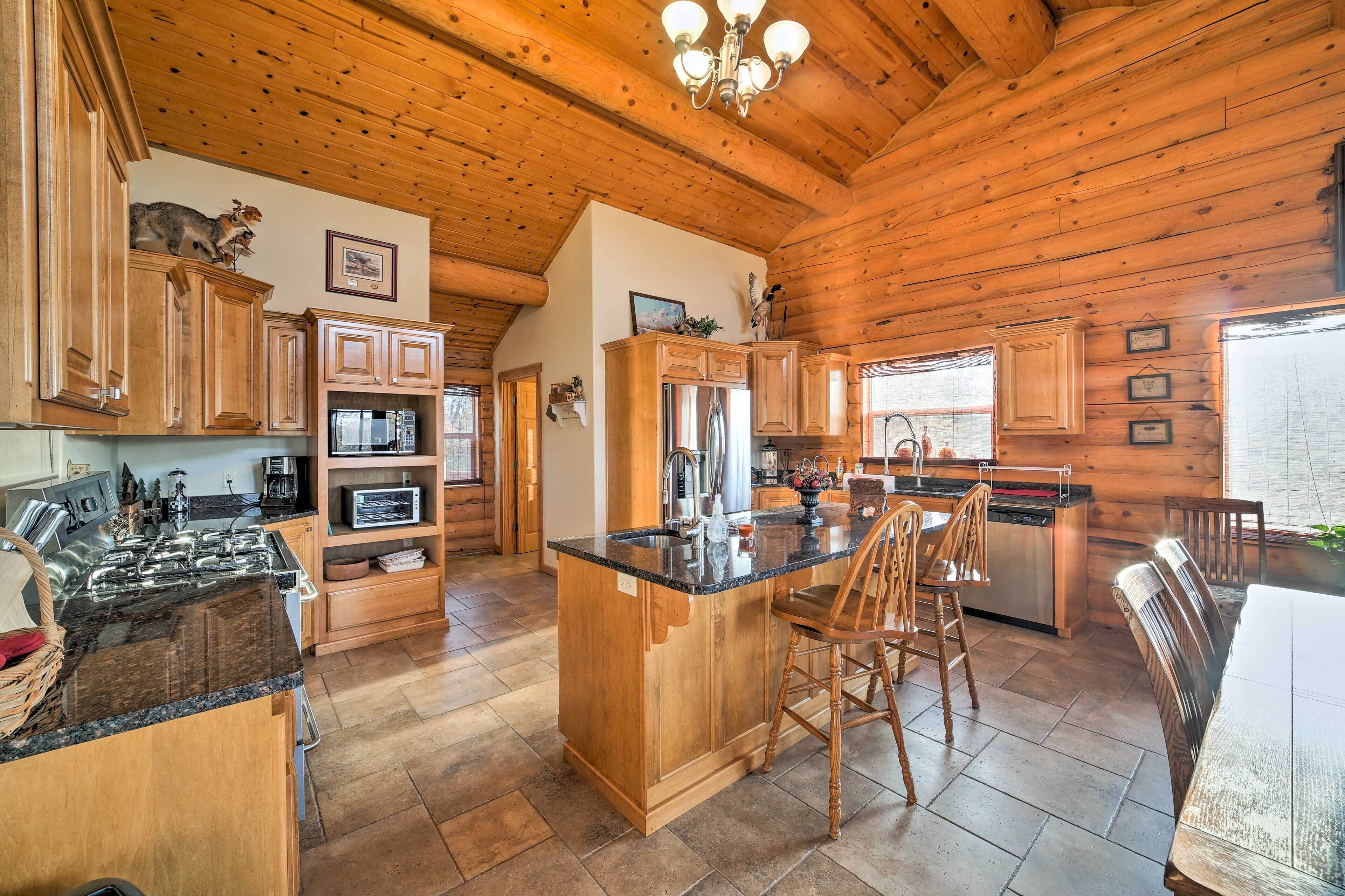 A spacious kitchen with wooden cabinets, a granite countertop, and a central island with bar stools.