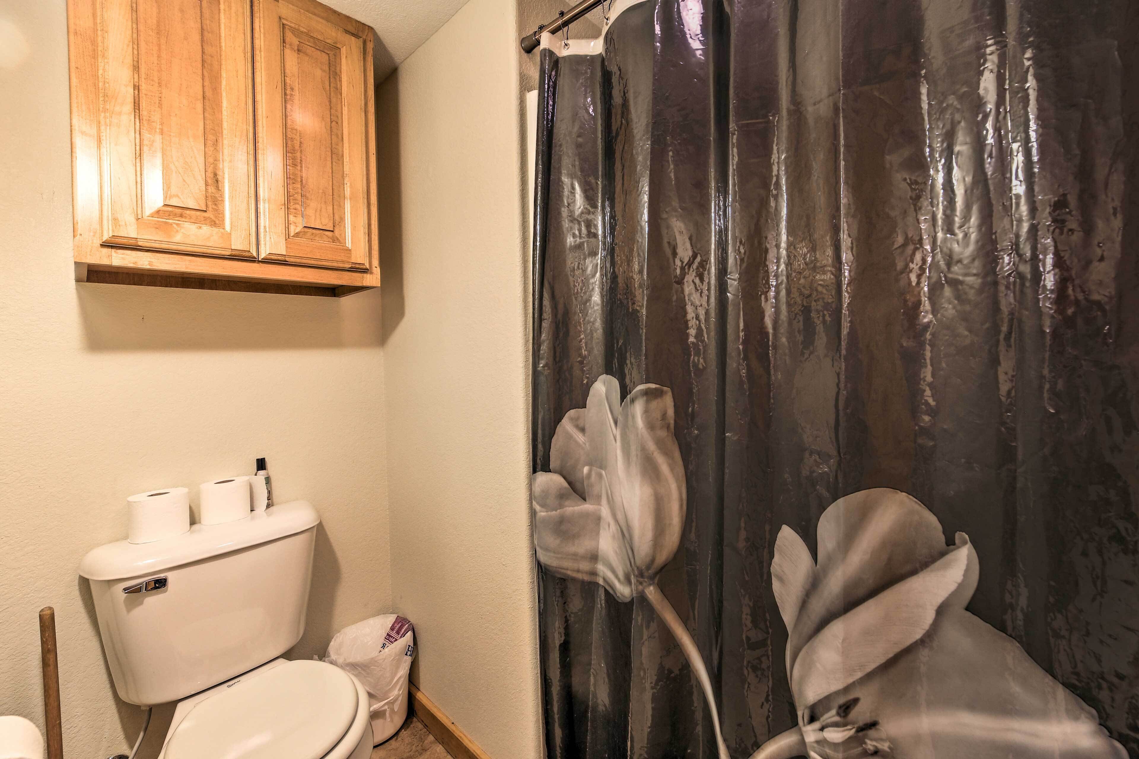 A bathroom with a toilet, wooden cabinets, and a shower curtain with a floral design.