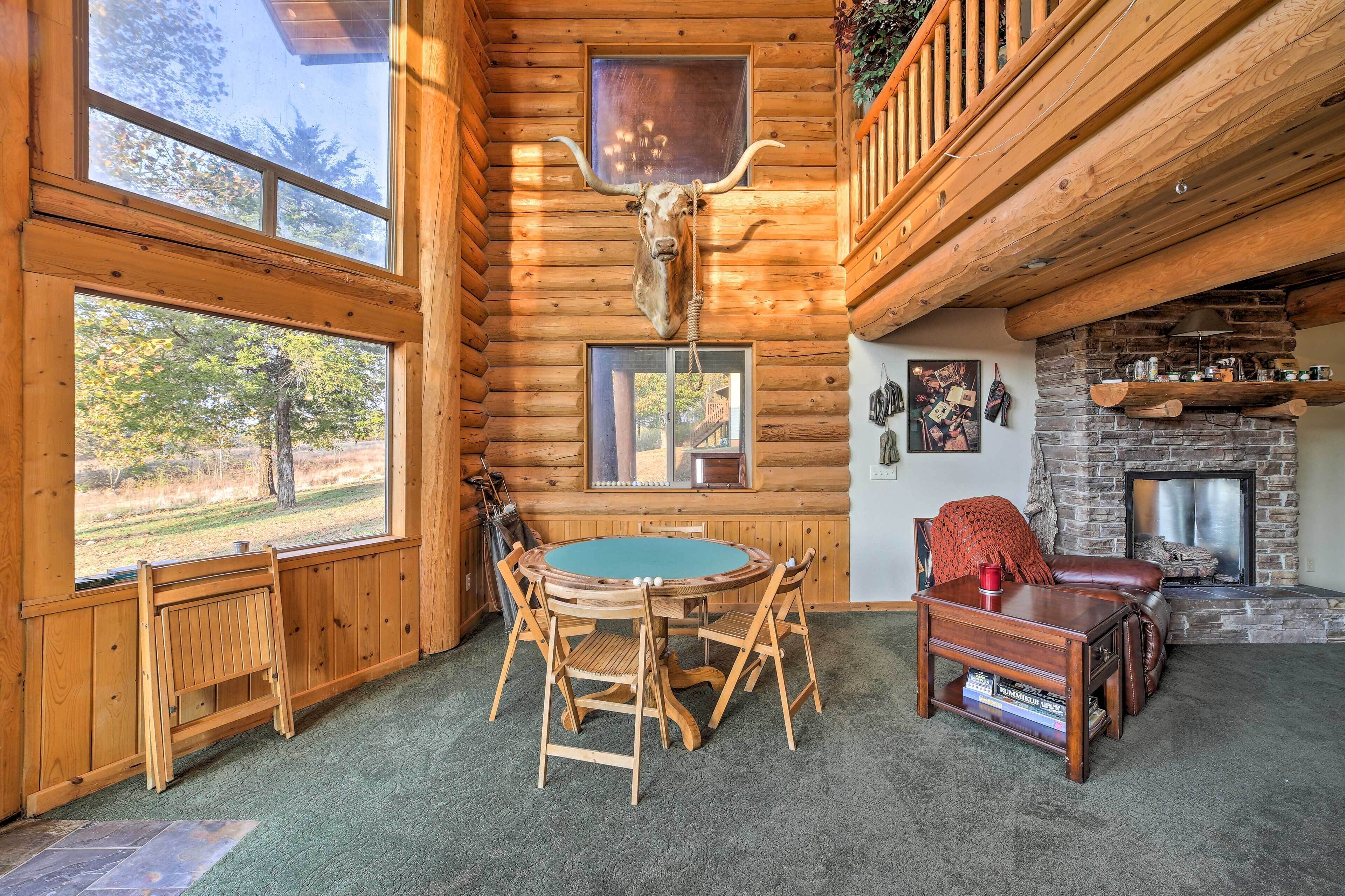 L'intérieur d'une cabane en rondins, avec une table à manger en bois, des chaises, une cheminée et une grande tête de taureau accrochée au mur.