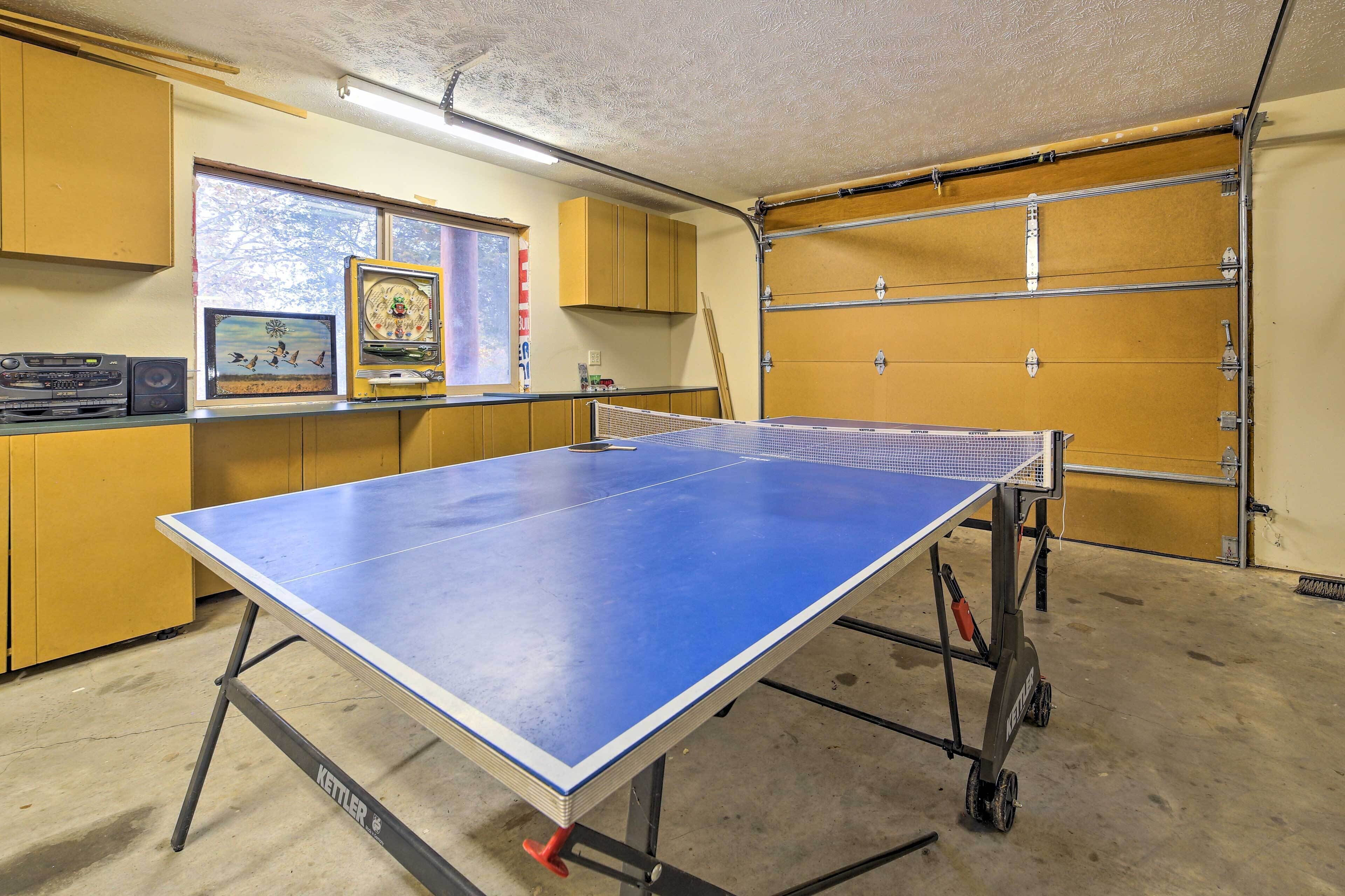 Ein Tischtennistisch in einem Raum mit gelben Schränken, einem Fenster mit Ausblick und einer Garage.