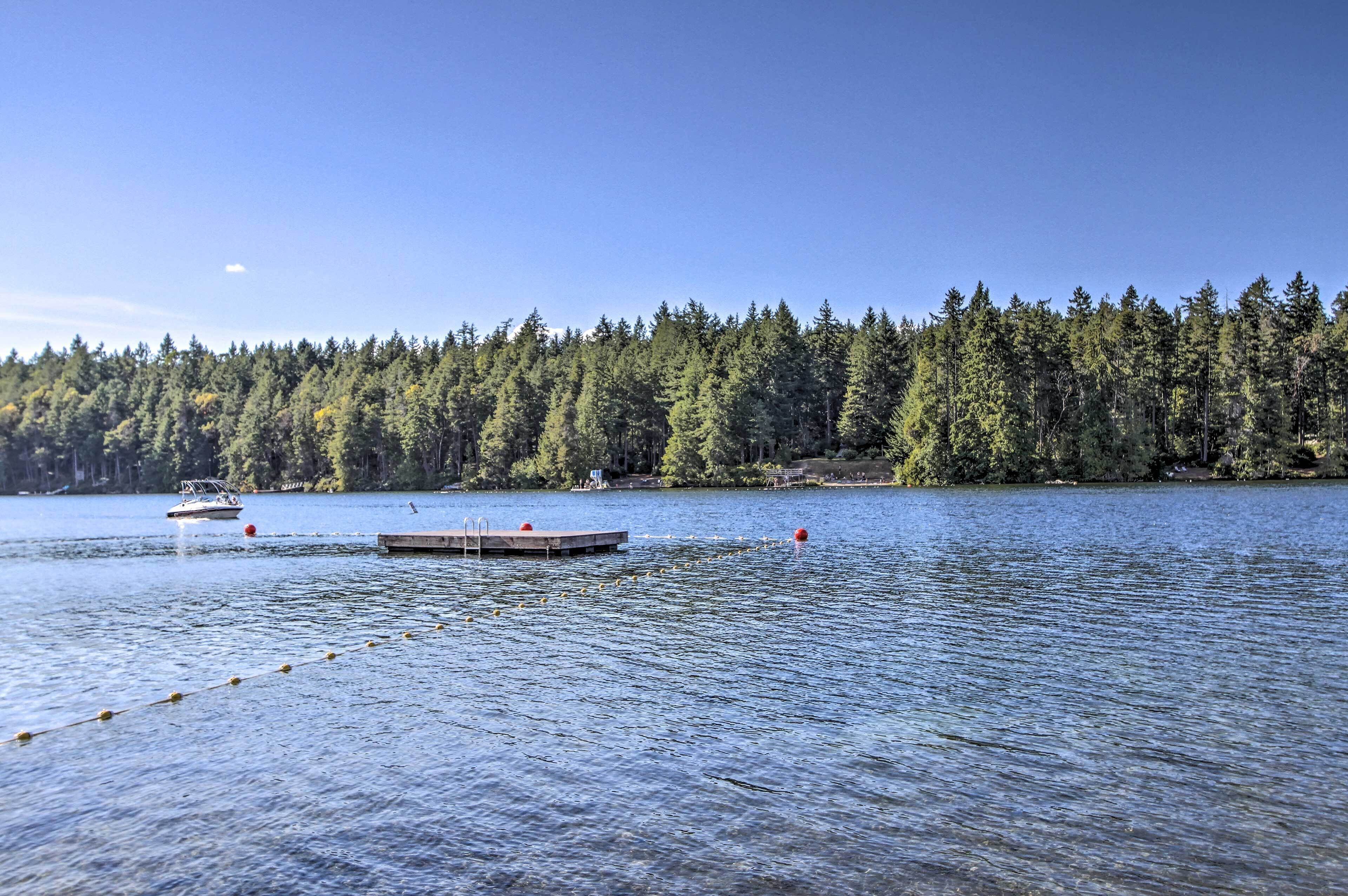 A calm lake with a dock and a row of trees in the background.