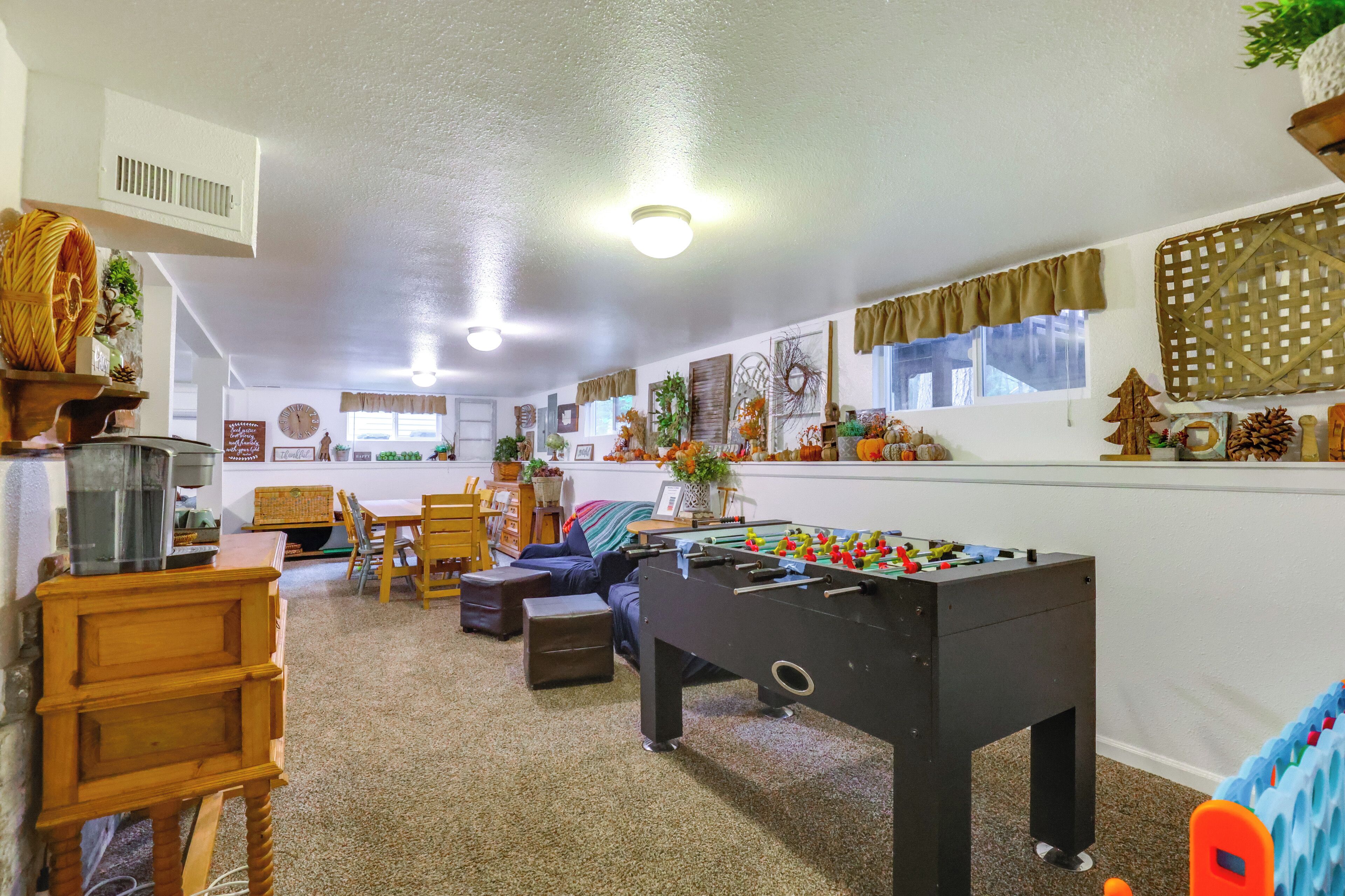 Una habitación acogedora con mesa de fútbol, muebles de madera y una ventana con cortinas.