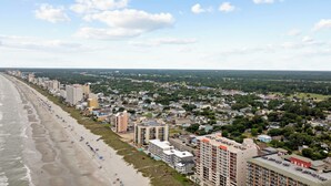 Eine Küstenstadt mit Strand, Hochhäusern und einer Mischung aus Wohn- und Geschäftsgebäuden.