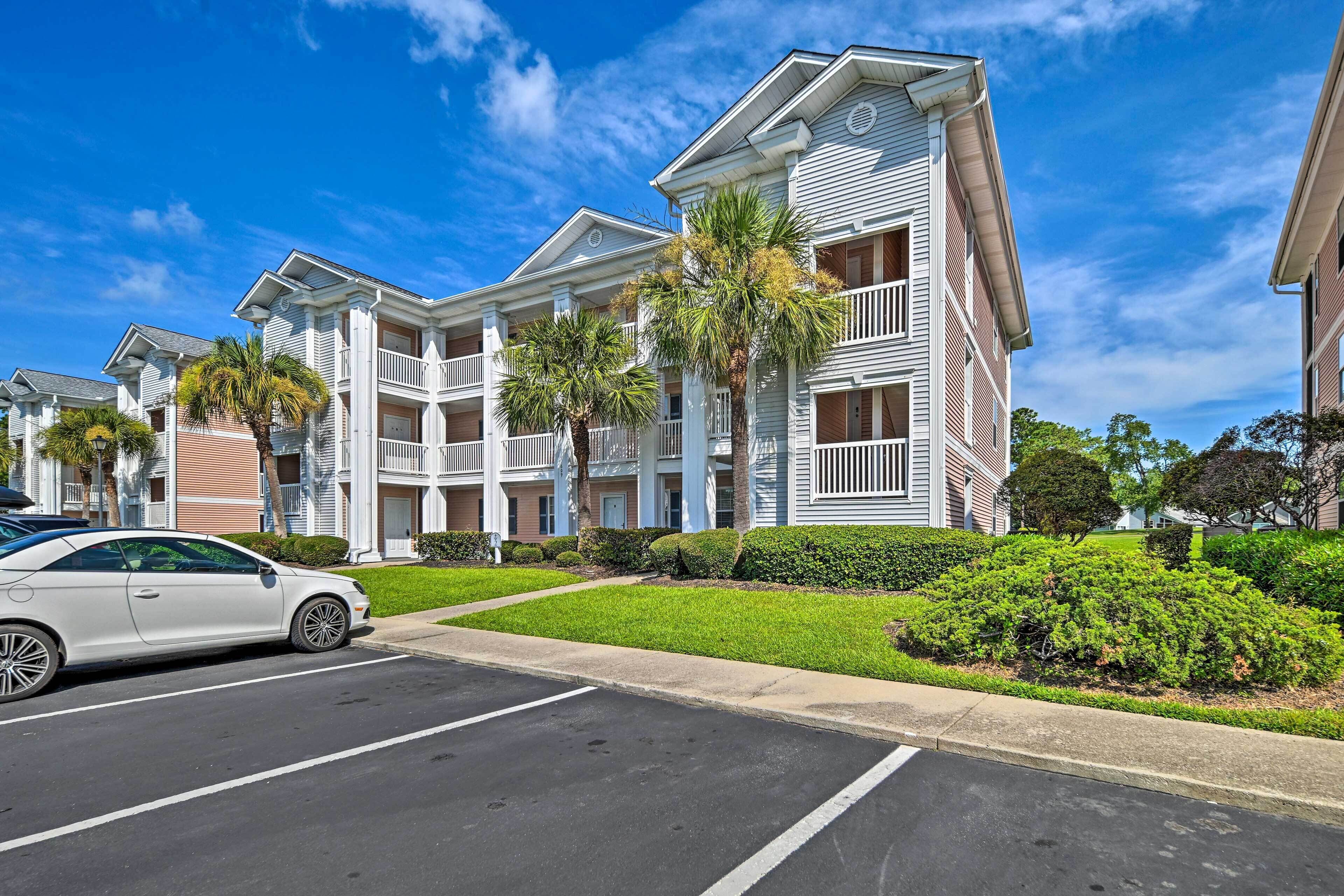 A multi-story residential building with a central courtyard, balconies, and a parking lot.