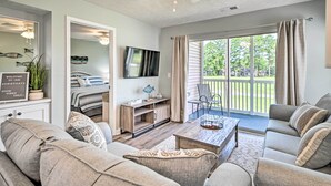 A spacious living room with a sofa set, a coffee table, and a TV. There is a balcony with a view of the outdoors. - Coastal Myrtle Beach Condo w/ Pool ~ 5 Mi to Beach (Myrtle Beach)