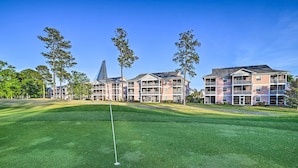 A well-maintained golf course with a putting green, surrounded by multi-story buildings with balconies, likely part of a hotel or resort. - Coastal Myrtle Beach Condo w/ Pool ~ 5 Mi to Beach (Myrtle Beach)