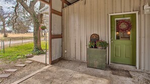 Un edificio rústico de madera con puerta verde, un pequeño porche y una corona en la puerta.