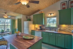 A kitchen with green cabinets, a wooden countertop, a ceiling fan, and a window with a view. - Quaint Countryside Casita: 45 Mi to Ft. Worth (Lipan)