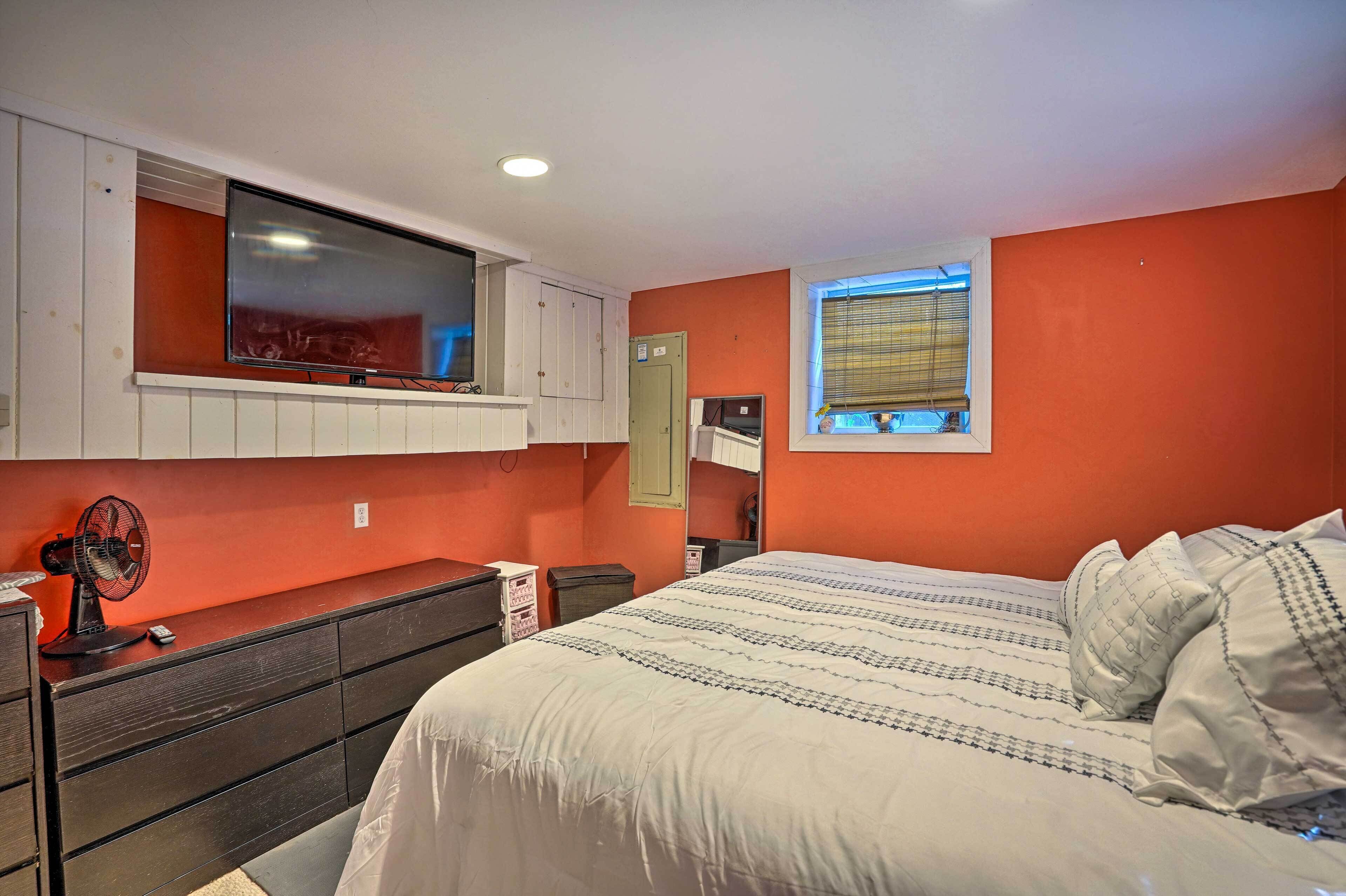 Un dormitorio con cama, cómoda, televisor y ventana.