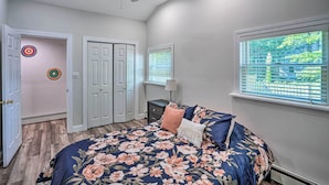 Un dormitorio con cama, ventilador de techo, ventana con persianas y puerta.