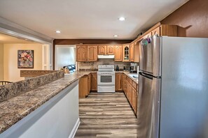 A kitchen with wooden cabinets, a stainless steel refrigerator, and a granite countertop.