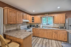 A kitchen with wooden cabinets, granite countertops, a stove, microwave, and a sink. - Pet-friendly Saratoga Springs Home w/ Pool! (Saratoga Springs)