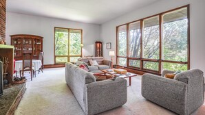 Un salón amplio con un gran ventanal, chimenea y zona de comedor.