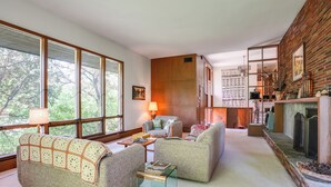Una sala de estar acogedora con ventanas amplias, chimenea y un espacio de descanso confortable.