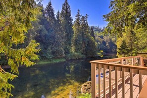 Ein Fluss, von dichtem Wald umgeben, mit einem Holzdeck und blauem Himmel.