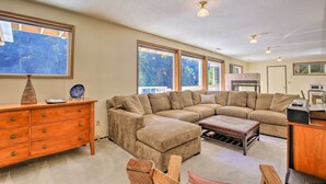 A spacious living room with a large sectional sofa, a wooden dresser, and a dining area. - Spacious Kalama Studio w/ Riverfront Deck! (Kalama)