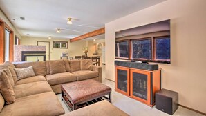 A spacious living room with a large L-shaped sectional sofa, a wooden bench, and a built-in entertainment unit with a flat-screen TV. - Spacious Kalama Studio w/ Riverfront Deck! (Kalama)
