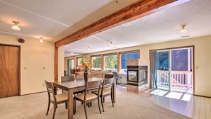 A spacious dining area with a wooden table and chairs, a built-in oven, and large windows offering views of the outdoors. - Spacious Kalama Studio w/ Riverfront Deck! (Kalama)
