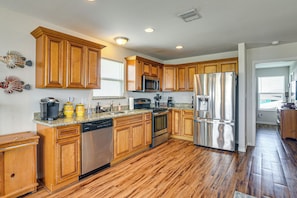 A kitchen with wooden cabinets, stainless steel appliances, and a herringbone-patterned floor.