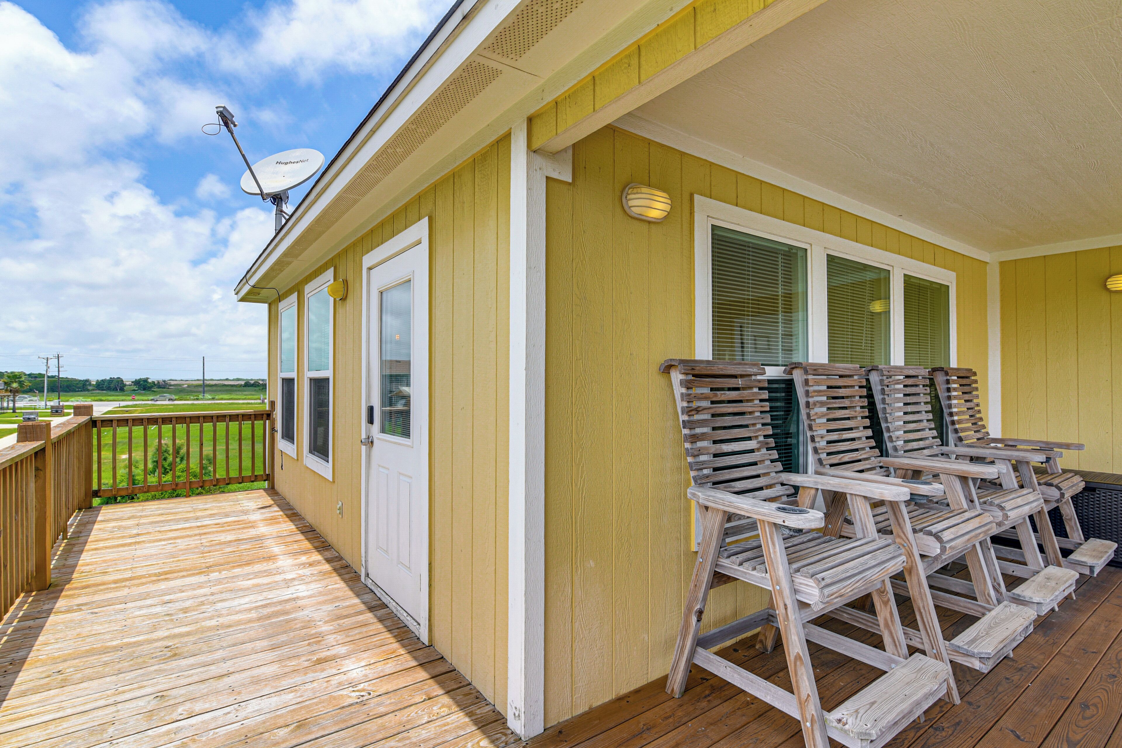 Une terrasse en bois avec des sièges d’extérieur, une porte et une antenne parabolique.