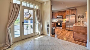 A spacious kitchen with wooden cabinets, a stainless steel refrigerator, and a large window with curtains. - Group Winter Retreat! Stunning Villa Near SDC (Branson)