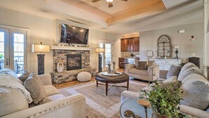 A spacious living room with a fireplace, comfortable seating, and a television mounted above it. - Group Winter Retreat! Stunning Villa Near SDC (Branson)