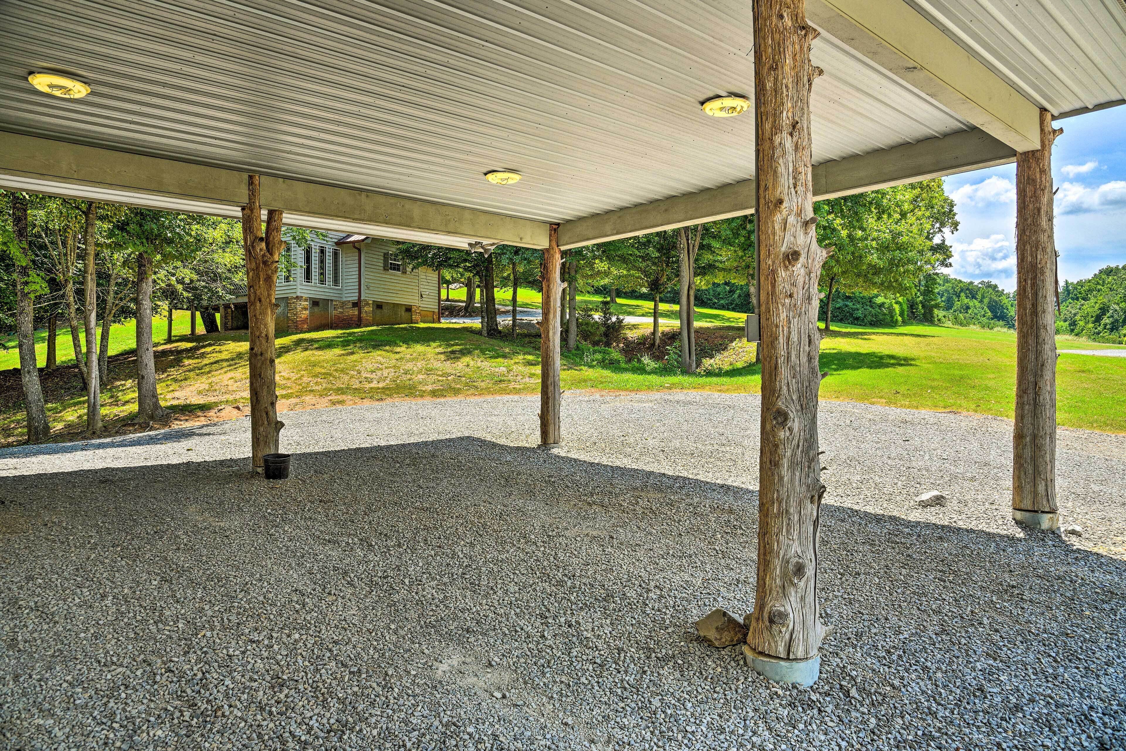 A covered outdoor area with a gravel floor, wooden posts, and a house in the background.