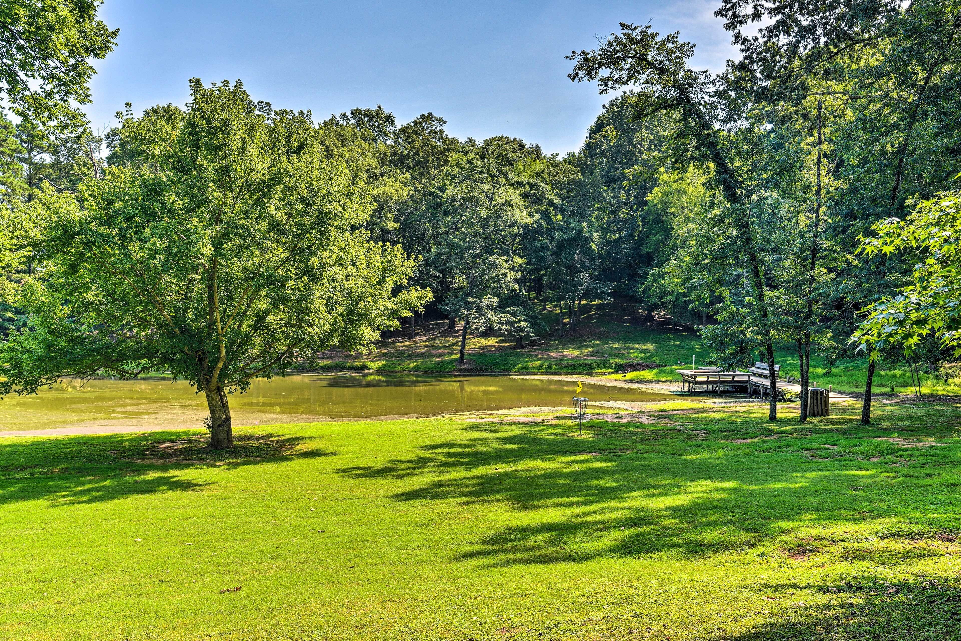 Ein Park mit Teich, Bäumen und einem Picknickplatz.
