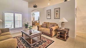 A living room with a sofa, coffee table, and side table, a large window with blinds, and a door leading to another room. - 12 Miles to Disney: Clermont Villa w/ Heated Pool (Clermont)