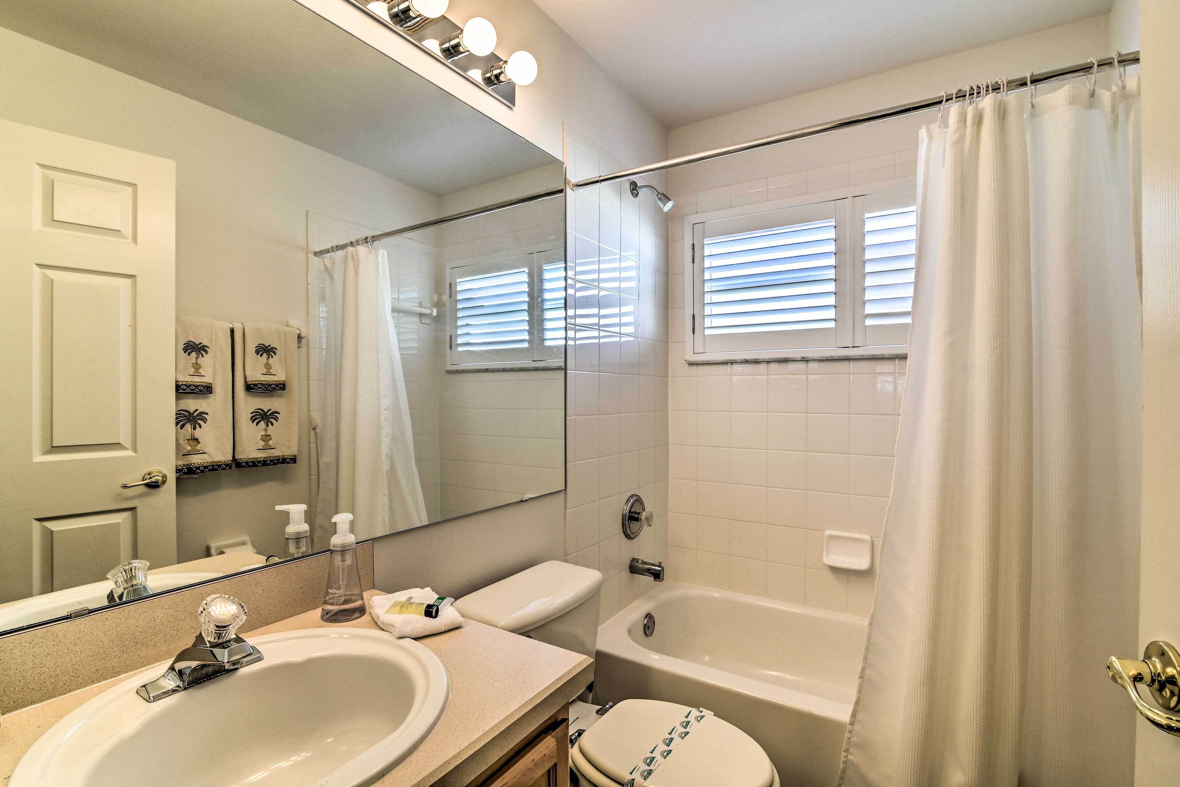 A bathroom with a sink, mirror, toilet, and bathtub.