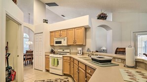 A kitchen with wooden cabinets, a microwave, stove, and a sink. - 12 Miles to Disney: Clermont Villa w/ Heated Pool (Clermont)