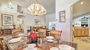 A dining area with a large table set for six, surrounded by wicker chairs, a chandelier, and framed artwork on the walls. - 12 Miles to Disney: Clermont Villa w/ Heated Pool (Clermont)