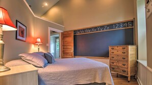 Un dormitorio con cama, cómoda, lámpara y una pizarra con letras y números.