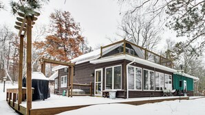 A wooden cabin with a covered deck, large windows, and a balcony. - Hike, Fish & Boat: Waterfront Home in Brainerd! (Brainerd)