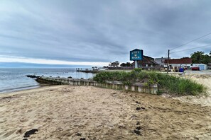 A beach with a sign for Cove Beach, a wooden pier, and a building with a red roof. - Saybrook Manor House, Walk to Cove Beach! (Old Saybrook)