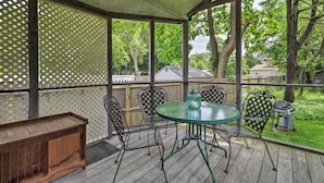 A covered outdoor patio with a wooden bench, metal chairs, and a glass table. - Saybrook Manor House, Walk to Cove Beach! (Old Saybrook)