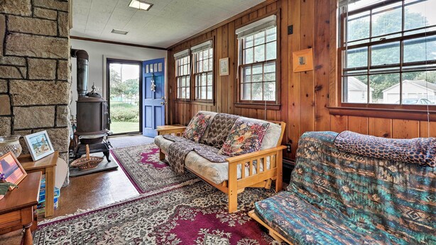 A cozy living room with a sofa, a fireplace, and a large window. - Saybrook Manor House, Walk to Cove Beach! (Old Saybrook)