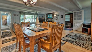 A dining area with a wooden table and chairs, a chandelier, and a stone fireplace. - Saybrook Manor House, Walk to Cove Beach! (Old Saybrook)