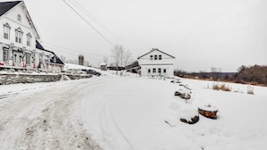 A snow-covered rural road with houses on either side. - Historic Carriage House < 20 Mi Elk Mtn: Hike, Ski (Lakewood)