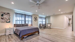 A bedroom with a bed, bedside tables, a ceiling fan, and a view of a hallway. - Spacious Gulfport Home w/ Yard: 1 Mi to Beach (Gulfport)