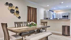 A dining area with a wooden table, chairs, and a bench. There is a kitchen in the background with cabinets and appliances. - Spacious Gulfport Home w/ Yard: 1 Mi to Beach (Gulfport)