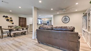 A spacious living area with a brown leather sofa, a dining table with chairs, and a kitchen in the background. - Spacious Gulfport Home w/ Yard: 1 Mi to Beach (Gulfport)