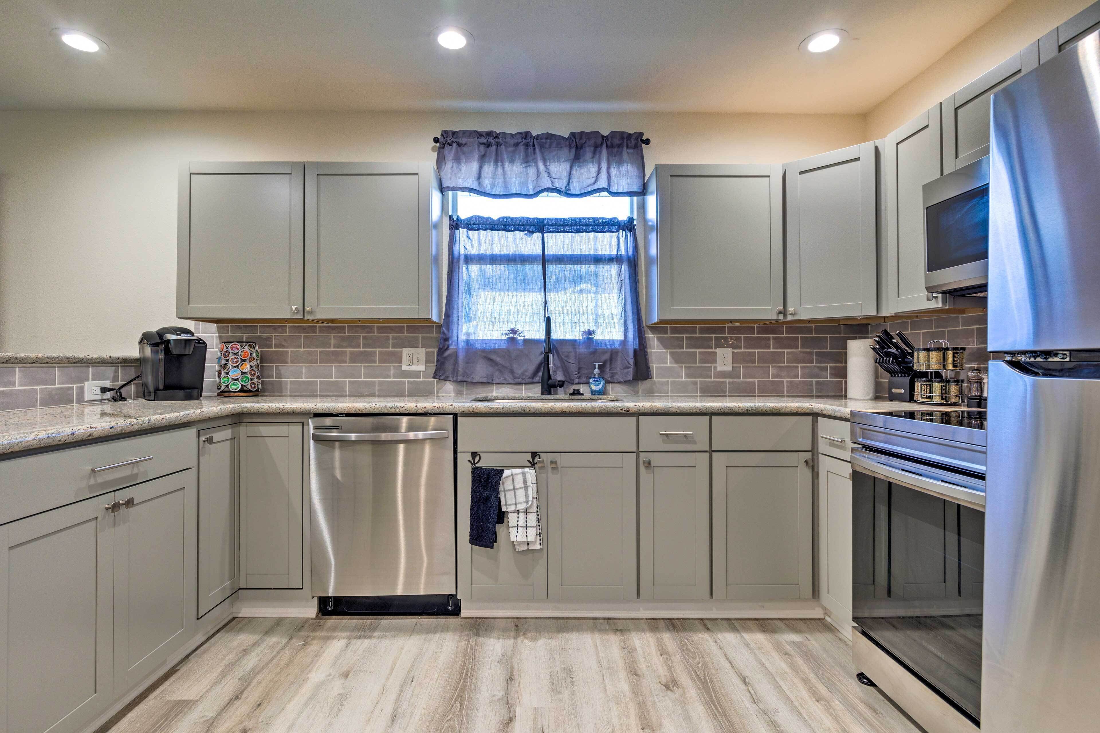 A modern kitchen with grey cabinets, a stainless steel dishwasher, and a built-in oven.