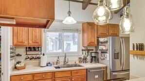 A kitchen with wooden cabinets, a stainless steel refrigerator, a sink, and hanging lights. - 1 Mi to Diamond Peak Ski Resort: Forest-view Condo (Incline Village)