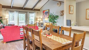A cozy living room with a red sofa, wooden dining table, and chairs. There is a window with curtains, a plant, and a painting on the wall. - 1 Mi to Diamond Peak Ski Resort: Forest-view Condo (Incline Village)