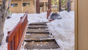 A snow-covered staircase with wooden railings leading to a building with a beige exterior and a balcony. - 1 Mi to Diamond Peak Ski Resort: Forest-view Condo (Incline Village)